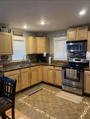 a kitchen with wooden cabinets and a stove top oven at Lakehouse Hot Tub & Pool close to Ark Encounter in Corinth