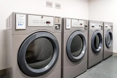 four washing machines are lined up in a laundrette at TownePlace Suites by Marriott New Philadelphia in New Philadelphia