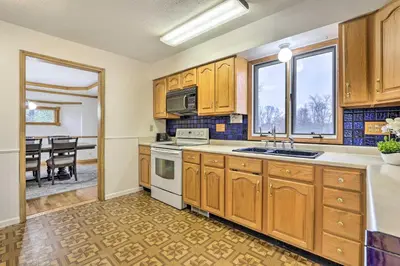 a kitchen with wooden cabinets and a dining room at Natures Haven Farmhouse in Pickerington with Deck in Pickerington