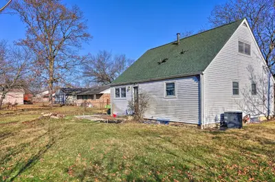 a white house with a green roof on a field at 4-Bedroom Cincinnati Vacation Rental! in Cincinnati