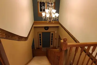 a hallway with a staircase with a chandelier at House On Grass Runway with Fly-In/Fly-Out Access in Tecumseh