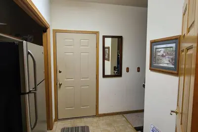 a hallway with a white door and a refrigerator at House On Grass Runway with Fly-In/Fly-Out Access in Tecumseh
