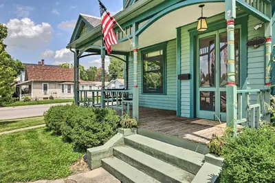 a green house with a porch with an american flag at NEW Grand Historic Home - 4 Mi to WEC! in Wilmington