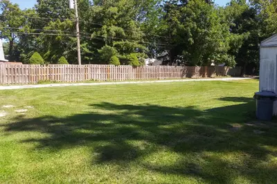 a yard with a fence and a large shadow of a tree at Eastlake Home with Patio Less Than 1 Mi to Lake Erie! in Eastlake