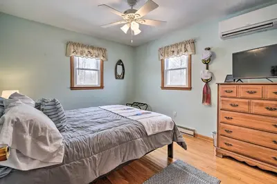 a bedroom with a bed with a ceiling fan and a dresser at Waterfront Lakeview Cottage with Dock and Lift! in Lakeview