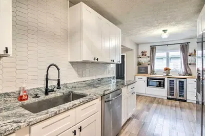 a kitchen with white cabinets and a sink at Cozy Ohio Retreat with Deck, Hot Tub and Grill! in Broadview Heights