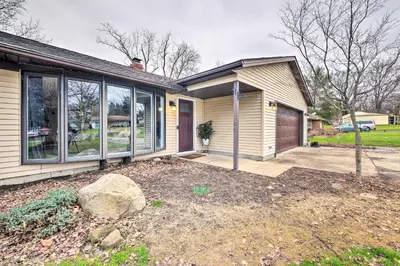 a house with a yard with a driveway at Cozy Ohio Retreat with Deck, Hot Tub and Grill! in Broadview Heights
