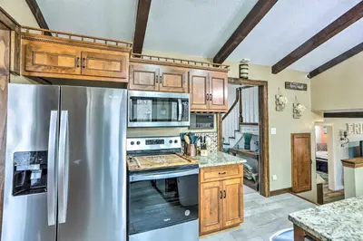 a kitchen with a stainless steel refrigerator and wooden cabinets at Vermilion River Home with Hot Tub and Private Dock! in Vermilion