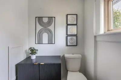 a bathroom with a toilet and some pictures on the wall at The Akron Retreat: Modern 3-Bedroom Oasis in Akron