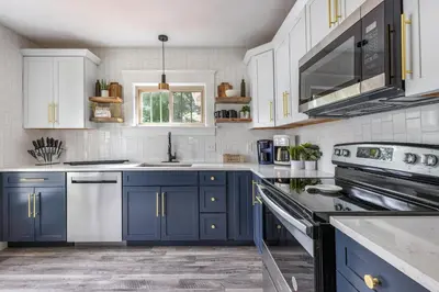 a kitchen with blue cabinets and white appliances at The Akron Retreat: Modern 3-Bedroom Oasis in Akron
