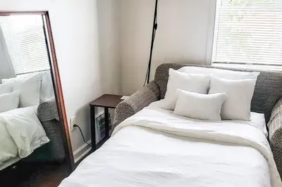 a bed with white sheets and pillows in a room at Cozy Cottage 10 mins to DTWN CLE Free Parking in Euclid