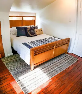 a bedroom with a large bed with a wooden headboard at Cozy Cottage 10 mins to DTWN CLE Free Parking in Euclid