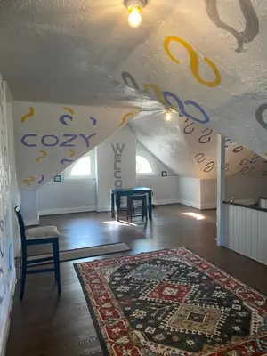 an attic room with a table and a rug at Awesome Attic Studio Private Room 3A in Cincinnati