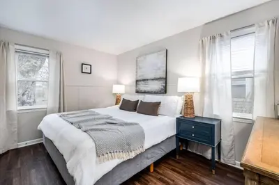 a bedroom with a large bed and two windows at City Boho ✦ New Kitchen ✦ King Bed ✦ WFH in Bexley