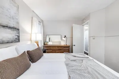 a white bedroom with a bed and a mirror at City Boho ✦ New Kitchen ✦ King Bed ✦ WFH in Bexley
