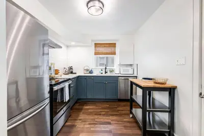 a kitchen with blue cabinets and a wooden floor at City Boho ✦ New Kitchen ✦ King Bed ✦ WFH in Bexley