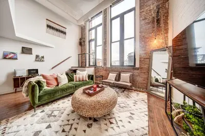a living room with a green couch and a brick wall at Waterfront Cleveland Apt about 1 Mi to Downtown in Cleveland
