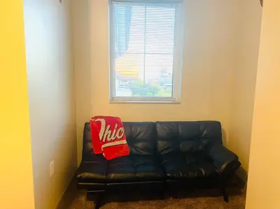 a black leather couch in a room with a window at King Size with OSU Theme! in Columbus