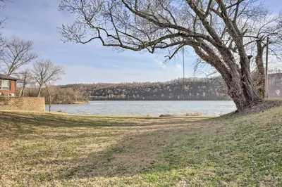 a tree on a hill next to a body of water at Manchester Getaway on Ohio River Scenic Byway in Manchester
