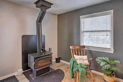 a living room with a wood stove and a chair at Peaceful Cottage about 8 Mi to Downtown Toledo! in Toledo