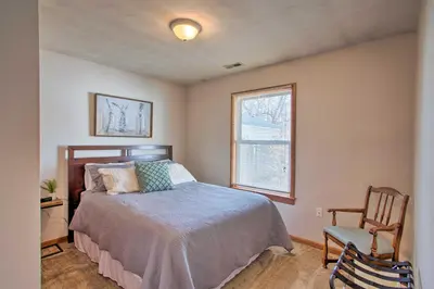 a bedroom with a bed and a chair and a window at Peaceful Cottage about 8 Mi to Downtown Toledo! in Toledo