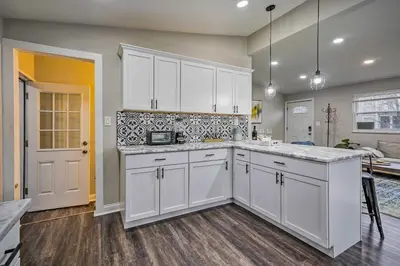 a kitchen with white cabinets and a living room at German Village Getaway with Grill 4 Mi to OSU! in Columbus