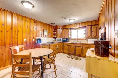 a kitchen with wooden cabinets and a table and chairs at Pet-Friendly Youngstown Cottage with Yard in Youngstown