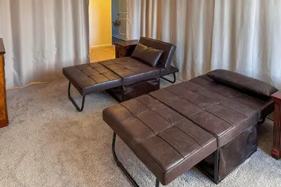 a living room with a leather chair and a stool at Private Backyard! Spacious Home 25 Mi to Columbus in New Albany