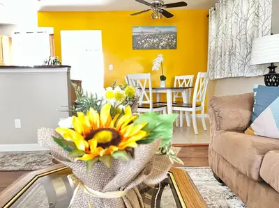 a living room with yellow walls and a vase of sunflowers at Sunny Stay Bright and Cozy Suite 1 in Cincinnati