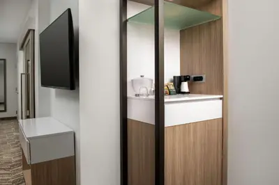 a room with a kitchen with a counter and a tv at SpringHill Suites by Marriott Cincinnati Mason in Mason