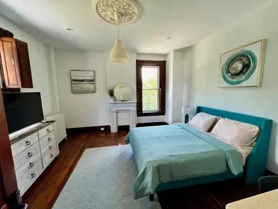 a bedroom with a blue bed and a television at Skyline Retreat Spacious Elegance Queen Suite 2 City Views in Cincinnati