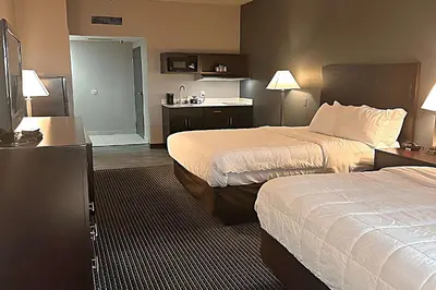 a hotel room with two beds and a kitchen at Suburban Studios Montpelier in Montpelier