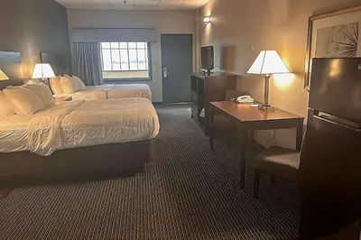a hotel room with two beds and a desk at Suburban Studios Montpelier in Montpelier
