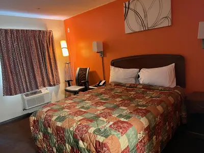 a bedroom with a bed with an orange wall at Lebanon Inn Motel in Lebanon