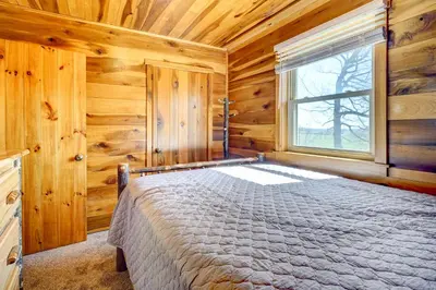a bedroom with a bed in a wooden cabin at Racine Vacation Rental 25 Mi to Athens! in Racine