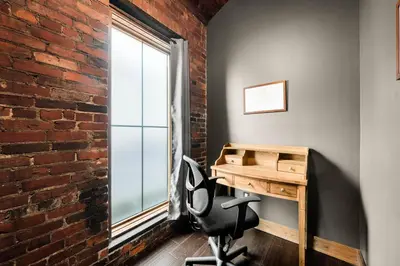an office with a brick wall and a desk and a window at The Chandler Hotel in Madison
