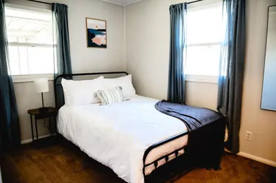 a bedroom with a large bed with blue curtains at Urban Cottage: Homey & Convenient in Huntington