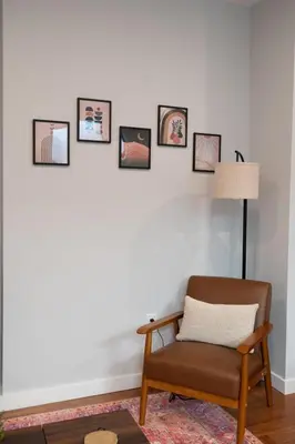 a living room with a chair and pictures on the wall at Prime OTR steps to Vine St, Lux Full Bed, Workspace, fast WiFi, 50in Smart TV, Sleeps 3ppl in Cincinnati