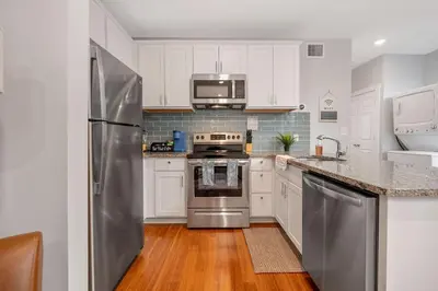 a kitchen with white cabinets and a stainless steel refrigerator at Prime OTR steps to Vine St, Lux Full Bed, Workspace, fast WiFi, 50in Smart TV, Sleeps 3ppl in Cincinnati