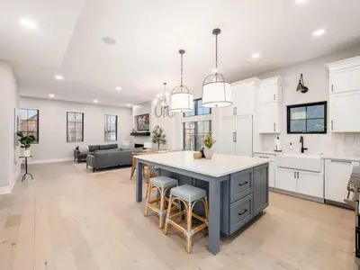 a kitchen and living room with white cabinets and a large island at Chateau in the Village - Brand New 3BD 5BA in Columbus