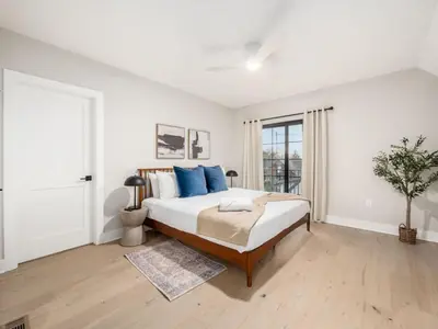 a white bedroom with a large bed with blue pillows at Chateau in the Village - Brand New 3BD 5BA in Columbus