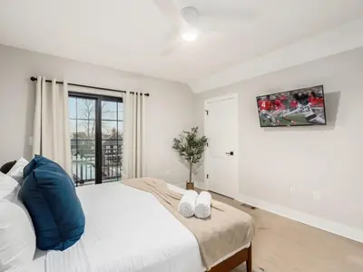 a white bedroom with a large bed with blue pillows at Chateau in the Village - Brand New 3BD 5BA in Columbus