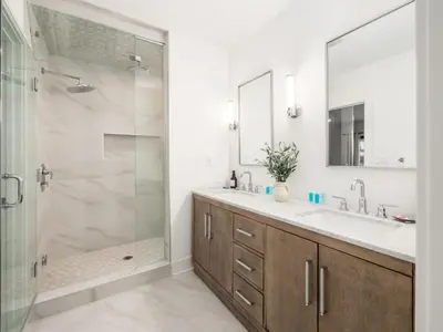 a bathroom with a shower and a sink and a mirror at Chateau in the Village - Brand New 3BD 5BA in Columbus