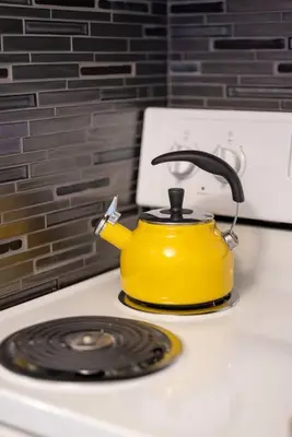 a yellow tea kettle sitting on top of a stove at King & Queen Memory foam beds! 2-4c Georgetown Villas in Fairview Park