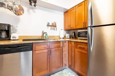 a kitchen with wooden cabinets and a stainless steel refrigerator at King & Queen Memory Foam Beds 2-2b Georgetown Villas in Fairview Park