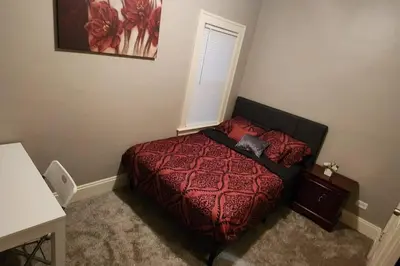 a bedroom with a bed with a red comforter at Comfy 3brd in Cleveland in Cleveland Heights