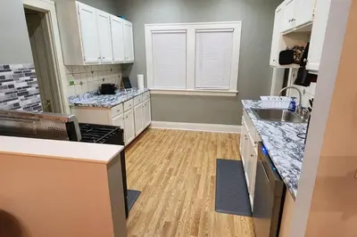 a kitchen with white cabinets and a wooden floor at Comfy 3brd in Cleveland in Cleveland Heights